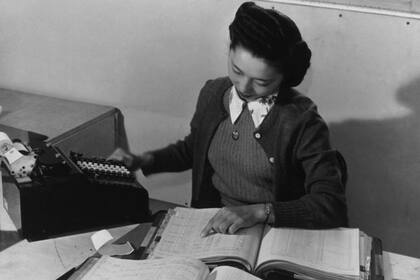 Contadora Teruko Kiyomura actualizando manualmente varios libros de contabilidad en 1943