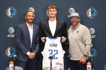 Cooper Flagg posa con la camiseta número 32 en el medio, siendo presentado por el presidente de operaciones y gerente general de los Dallas Mavericks, Nico Harrison, a su izquierda, y Jason Kidd, quien será su entrenador, a la derecha