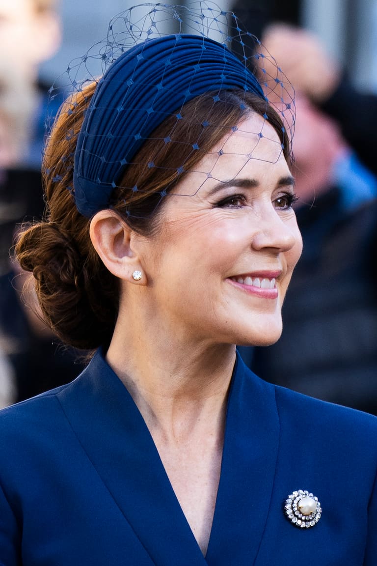 El broche Pearl Poiré de perla y diamantes que la reina Mary llevó sobre un traje azul. En la otra imagen, con la diadema de oro y camafeos que estuvo en las sombras por más de 140 años