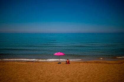 Un hombre toma el sol en la playa de Glyfada antes de la reapertura al turismo en la zona