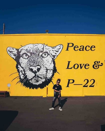 Corie Mattie, una artista también conocida como LA Hope Dealer, se para frente a un mural que pintó en el vecindario Silver Lake de Los Ángeles que muestra a P-22