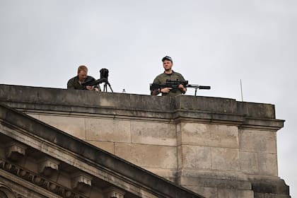 Francotiradores de la policía sostienen sus armas mientras están de guardia en el techo del Palacio de Buckingham.