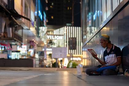 Un hombre musulmán se sienta en calle vacía frente a un distrito comercial cerrado en el centro de Kuala Lumpur, Malasia