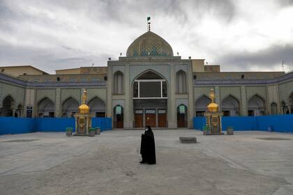 Una mujer con una máscara camina en el patio de una mezquita, en Shahr-e-Ray, al sur de Teherán, Irán