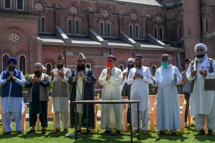 Los devotos musulmanes, cristianos, hindúes y sij se reúnen mientras ofrecen oraciones por el final de la pandemia de coronavirus fuera de la Catedral del Sagrado Corazón durante un bloqueo nacional impuesto por el gobierno como medida preventiva contra el coronavirus COVID-19, en Lahore, Paquistán