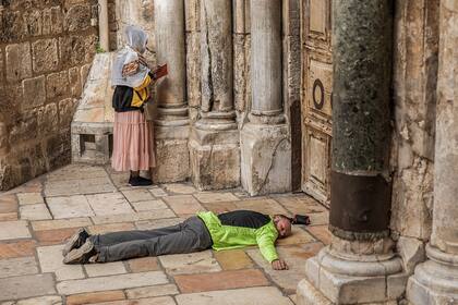 Jerusalén: una mujer reza mientras un hombre yace fuera de la puerta cerrada de la Iglesia del Santo Sepulcro