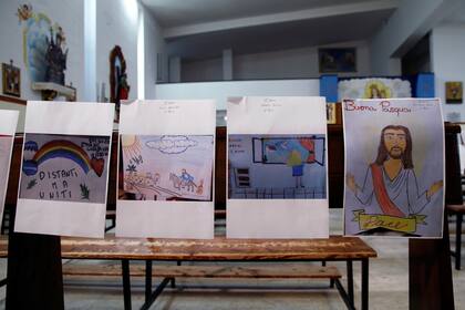 Los dibujos realizados por hijos de miembros de la congregación reemplazan a las personas y decoran los bancos durante la misa del Jueves Santo celebrada por el padre Fabio Vassallo en una iglesia "casi" vacía en Catania, Italia