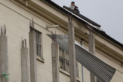 Un preso arroja las chapas que arrancó del techo del edificio