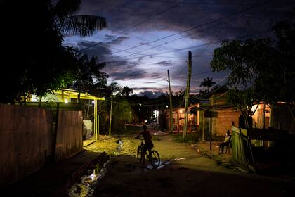 Un niño anda en bicicleta al anochecer a través de la comunidad del Parque de las Naciones Indígenas, calles angostas, llenas de basura y con agua sucia acumulada, son factores que aumentan los riesgos por la falta de higiene