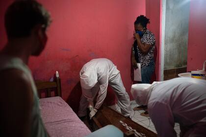 Los médicos retiran el cuerpo de un hombre que acaba de morir en su casa.