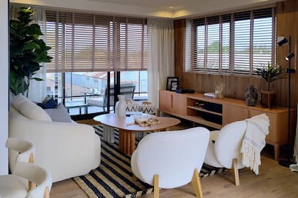 Cortinas americanas de madera; en la ventana más grande, tras unas de gasa 'Lime Cream' (ambas de Hunter Douglas por Delia Mucci). Poltronas de bouclé, alfombra, mesas de centro y consola (Estudio GOD).