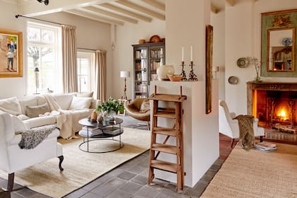 Cortinas de lino beige, alfombras de yute que delimitan sectores y mantas artesanales abrigando los sillones de estilo.