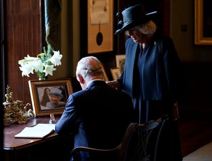 Crowds cheer as King Charles III and Camilla, the Queen Consort sign the visitors book during a visit to Hillsborough Castle, Belfast, Tuesday, Sept. 13. 2022. (Niall Carson/Pool photo via AP)