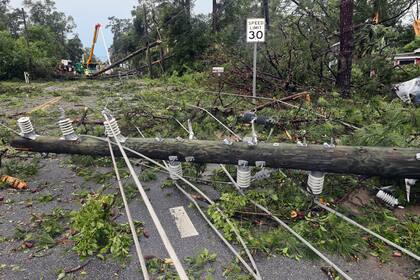 Cuadrillas de trabajadores retiran postes quebrados y cableado eléctrico derribado por los fuertes vientos, en una calle de Tallahassee, Florida, el viernes 10 de mayo de 2024. (AP Foto/Phil Sears)