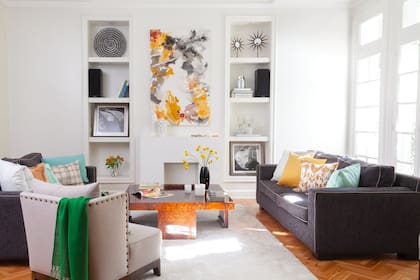 Cuadro de la serie ‘Orgánico’ firmado por Rosario. Mesa de raíz de nogal heredada. En los estantes, botellones que eran de su abuela y fotos de autos de competición, que eran del papá de Rosario. De los colores de las pinturas, surgieron los tonos de los almohadones y textiles