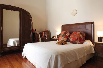 Cuando el dormitorio tiene techos altos nos da la libertad de jugar con la altura de la cabecera. En este caso, otra vez el cuero es protagonista. Los almohadones coloridos permiten descontracturar el sector