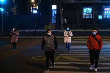 Cuatro personas cruzan una calle en China con máscaras