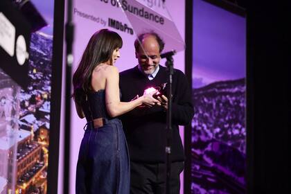 Dakota Johnson le entrega un premio al director Luca Guadagnino