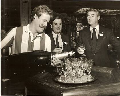 Dan Scoggin, a la derecha, observa a un camarero servir champán de una botella gigante