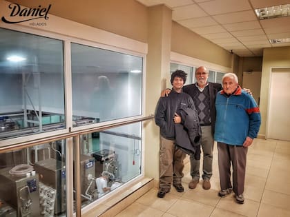 Daniel posa junto a Roberto, el heladero de su barrio, su mentor, quien le dio el primer trabajo y le enseñó el oficio. La imagen fue tomada en una visita a la planta de producción de Garín. Roberto fue junto a su sobrino nieto y probó el helado de su aprendiz.