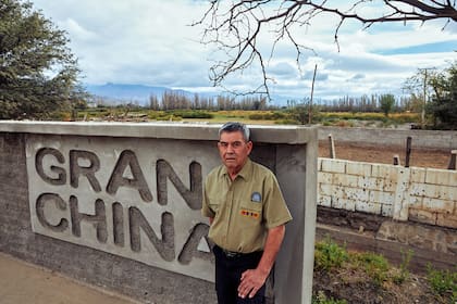 Daniel Rolando Guerra, presidente de la unión vecinal, junto al cartel que, en la entrada del pueblo, anuncia su nombre