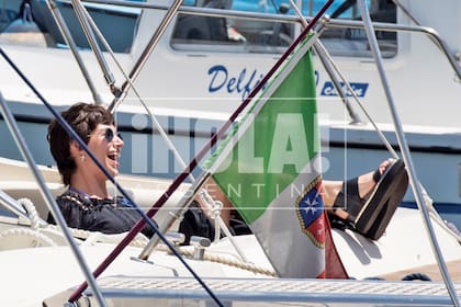 Úrsula bajó del taxi con una toalla en la mano. Su estilismo de playa estaba compuesto por un top negro con mangas largas, polleras con negro y sandalias con plataformas