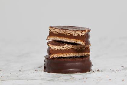 Dark chocolate and dulce de leche alfajores on a marble table.