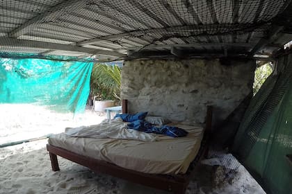 Glasheen dice que la vida en la isla es "pacífica, segura y satisfactoria". Arriba, su habitación, que tiene un piso de arena estilo náufrago