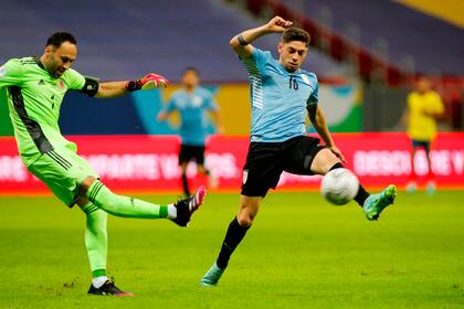David Ospina, el arquero récord, rechaza la pelota frente a la embestida de Federico Valverde (Photo by SILVIO AVILA / AFP)