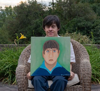 David posa junto al autoretrato que pintó en óleo