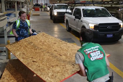 David Rosenbaum jr. y Devlin Cudd cargan madera contrachapada en vehículos mientras la gente compra suministros en la ferretería Stine antes de la posible llegada del huracán Laura el 26 de agosto de 2020 en Lake Charles, Louisiana