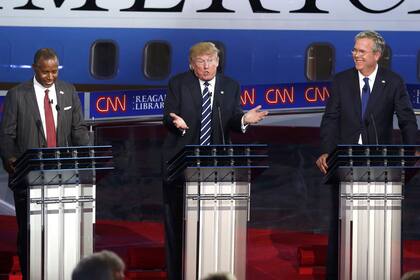 De izq. a der.: Ben Carson, Donald Trump y Jeb Bush, en el podio de las encuestas, en el centro del escenario