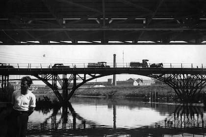 Debajo del nuevo puente, se observa el cruce del viejo: camiones y carros tirados a caballo en 1938.
