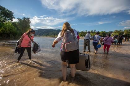 Decenas de personas llegan hasta un banco de arena para subir a improvisados gomones en el río Bermejo