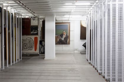 Decenas de "racks" con obras en una de las reservas del Moderno; al fondo se ve un retrato de Ignacio Pirovano, cuya colección  fue donada al museo, realizado en 1974/5 por Héctor Giuffré