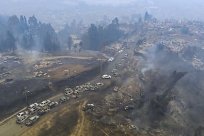 Decenas de vehículos dañados se alinean en una ruta después de que los incendios forestales arrasaron áreas residenciales en Lirquen, Chile.
