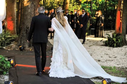 Del brazo de su padre, Guillermo Calabrese, la novia camina hacia el altar por un sendero de coronas de novia y orquídeas