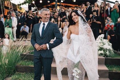 Del brazo de su padre, Paloma Goycochea luce un vestido firmado por su madre, la diseñadora
Ana Laura Merlo. Se trata de un modelo con corset
estructurado y falda con detalles en transparencias
e incrustaciones bordadas y velo largo de encaje