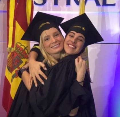 Delfina Lanusse y Chantal Leclercq se abrazan y sonríen durante un acto de graduación, ambas con toga y birrete en la Universidad Austral