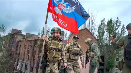 Denis Pushilin, jefe de la región de Donetsk controlada por Rusia, sostiene una bandera sobre un edificio dañado en Bakhmut, Ucrania.