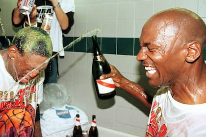 Dennis Rodman de los Chicago Bulls recibe cerveza y champán sobre su cabeza por su compañero de equipo Michael Jordan y otros un 14 de junio del 98, después de ganar el sexto juego de las Finales de la NBA contra los Utah Jazz en el Delta Center en Salt Lake City, UT . Los Bulls ganaron el juego 87-