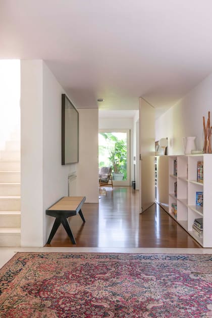 Desde el amplio pasillo de entrada ya se disfruta el remate verde que encuadra todo el living-comedor.