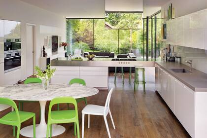 Desde la cara opuesta, muebles de cocina ‘LT’ de la marca italiana Boffi con mesadas de acero inoxidable y concreto gris. Mesa de comedor ‘Tulip’ con sillas de PVC.