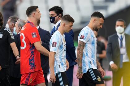 Desde la derecha, los jugadores argentinos Nicolás Otamendi, Giovani Lo Celso y Emiliano Martínez se retiran de la cancha tras la interrupción del partido contra Brasil por las eliminatorias del Mundial