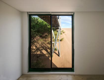 Desde la habitaciones se siente la relación entre la casa y el médano. Ventanas de aluminio 'Módena'.