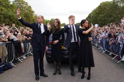 Desde la izquierda, el príncipe británico Guillermo, príncipe de Gales, Kate, princesa de Gales, el príncipe Harry y Meghan, duquesa de Sussex saludan a los miembros del público en el castillo de Windsor, tras la muerte de la reina Isabel II el jueves, en Windsor, Inglaterra, el sábado 10 de septiembre de 2022.