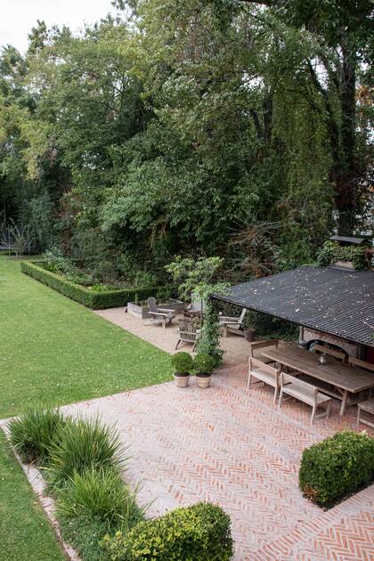 Desde la pérgola del quincho, se ve un diseño de huerta y fogón, a la sombra de Bauhinia forficata del vecino, y repitiendo la especie de este lado.