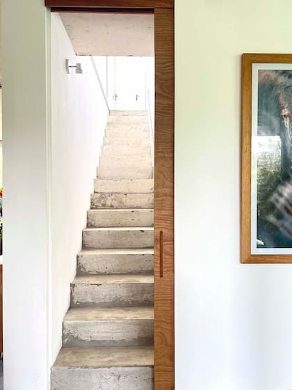 Desde la sala multiuso se accede a la planta alta por una escalera de cemento visto cerrada por una puerta corrediza.