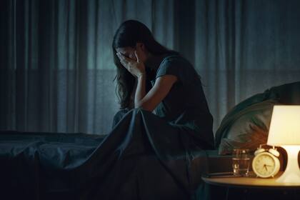 Desperate young woman sitting alone in bed at night, she is depressed and suffering from insomnia