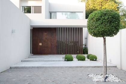 Después: así se lucen después de la obra las bolas de buxus y un arbolito de Eugenia myrtifolia podado. La trama de las tiras de chapa oxidada deja entrever un pequeño cantero con especies que toleran sombra